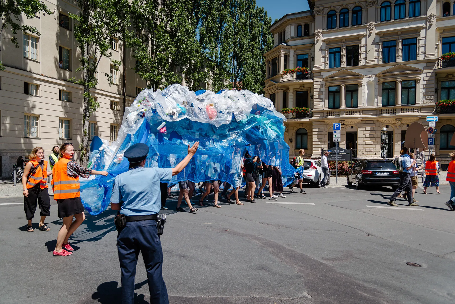 Die Plastikwelle zieht zwischen Altbauten durch die Stadt, ein Polizist regelt den Verkehr